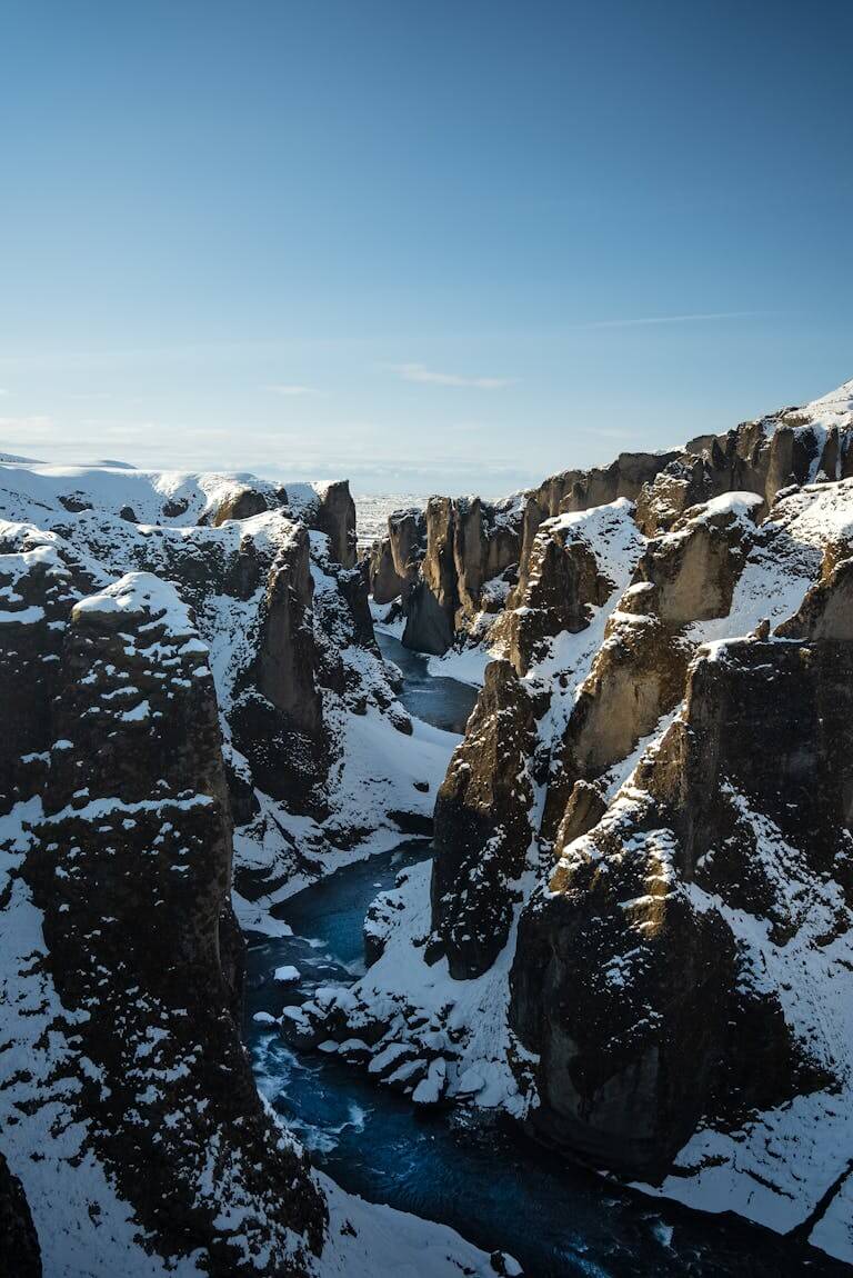 A breathtaking view of the snow-covered Fjaðrárgljúfur canyon in Iceland with a winding river.