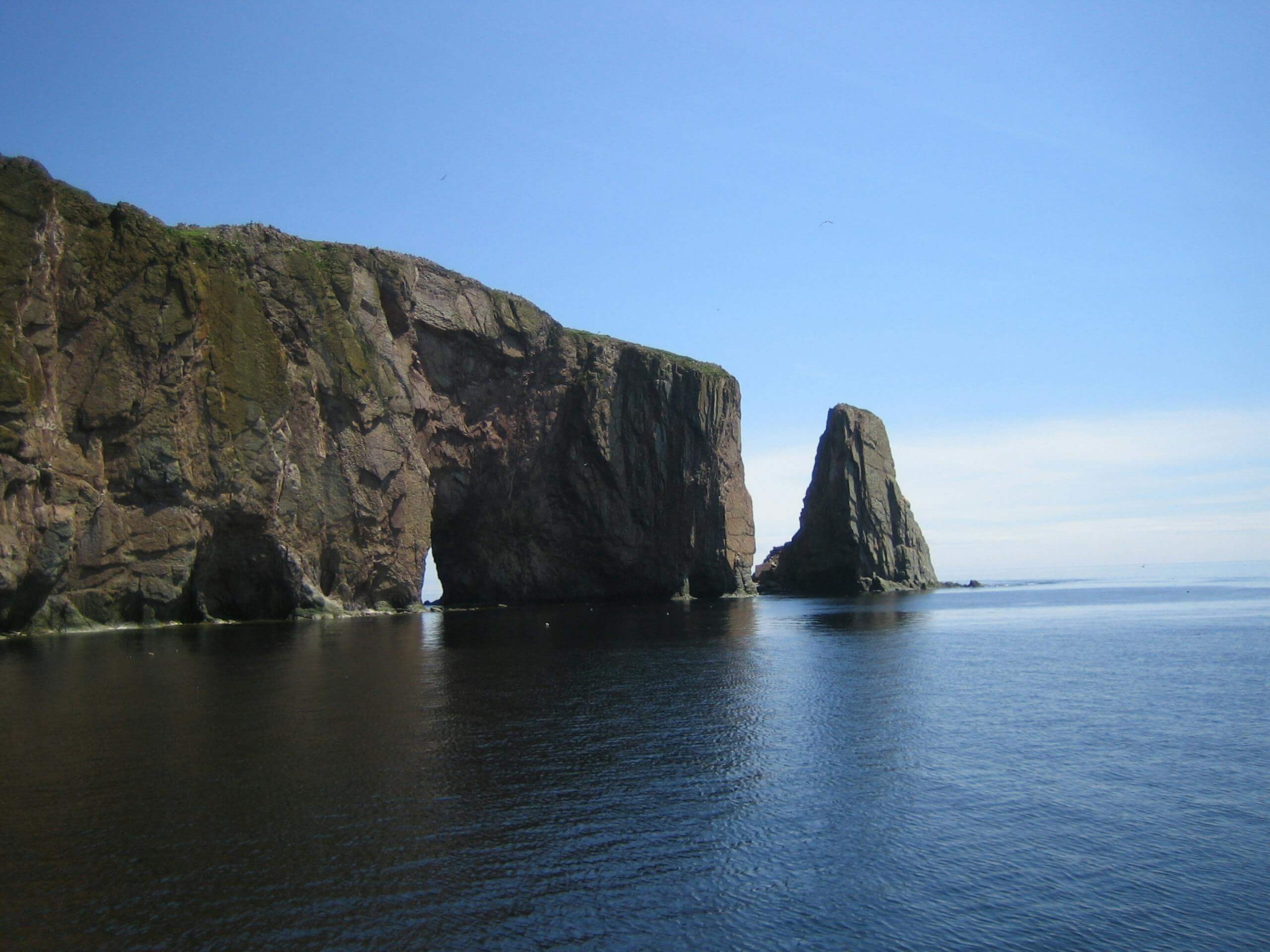 Beautiful view of Percé Rock against the clear blue sky and ocean waters in Quebec.