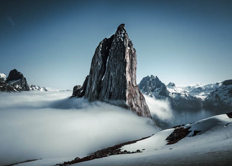 Breathtaking view of fog-draped rugged mountains on a winter twilight with snow.