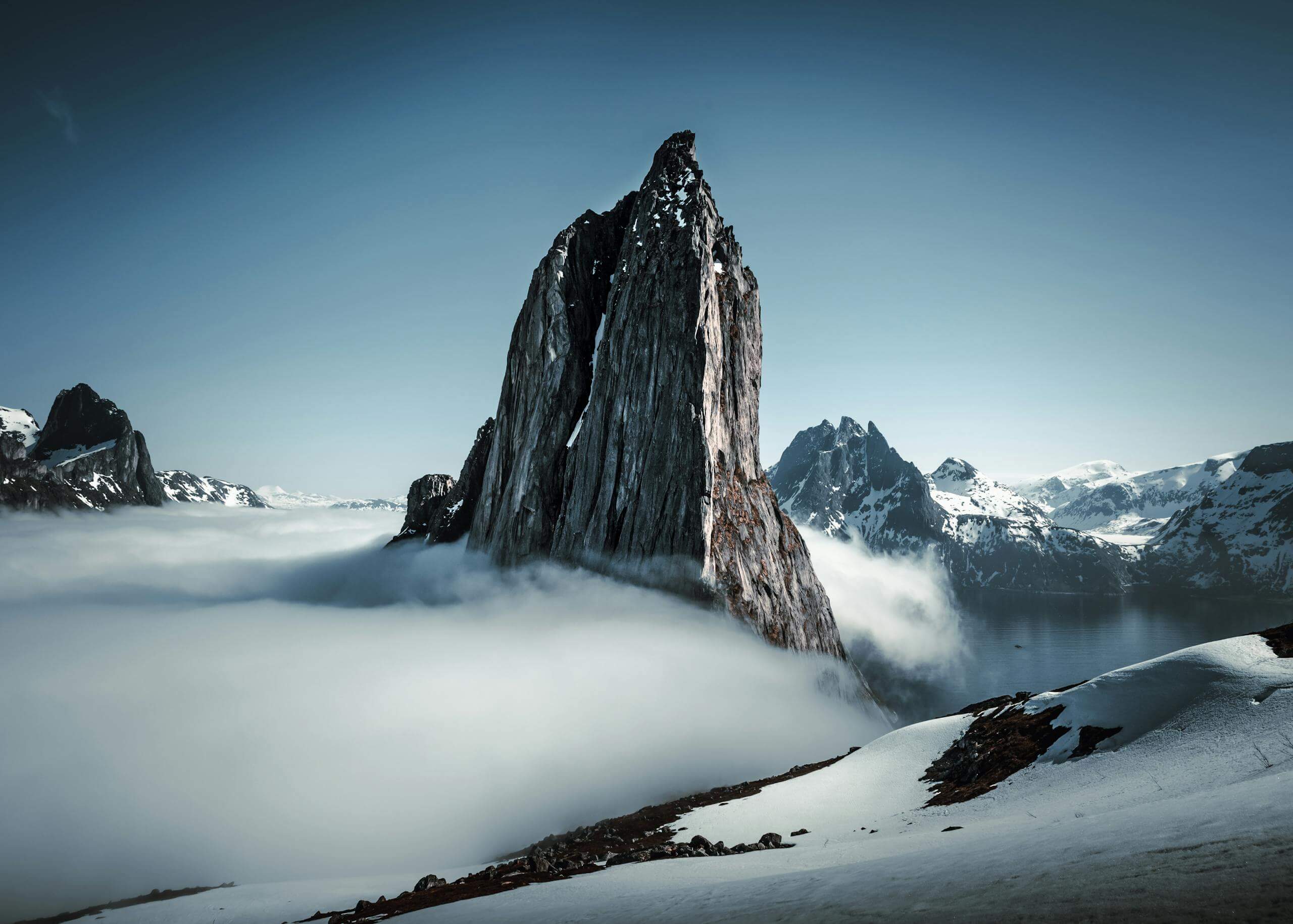 Breathtaking view of fog-draped rugged mountains on a winter twilight with snow.